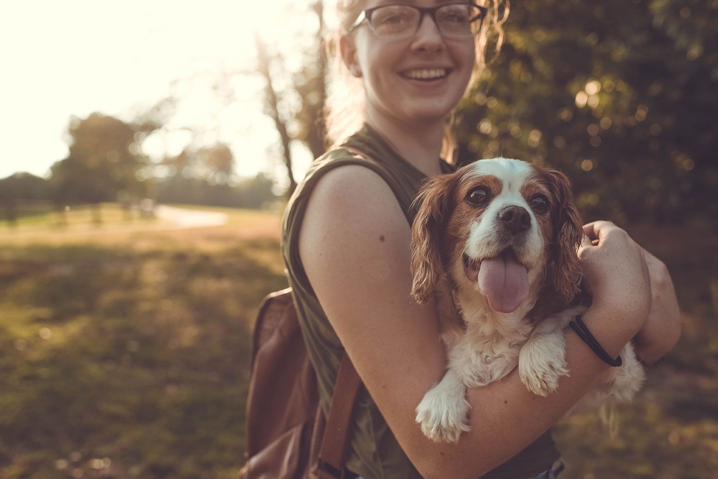 Young girl with glasses and backpack holding a small dog filtered sunlight Fear and anxiety
